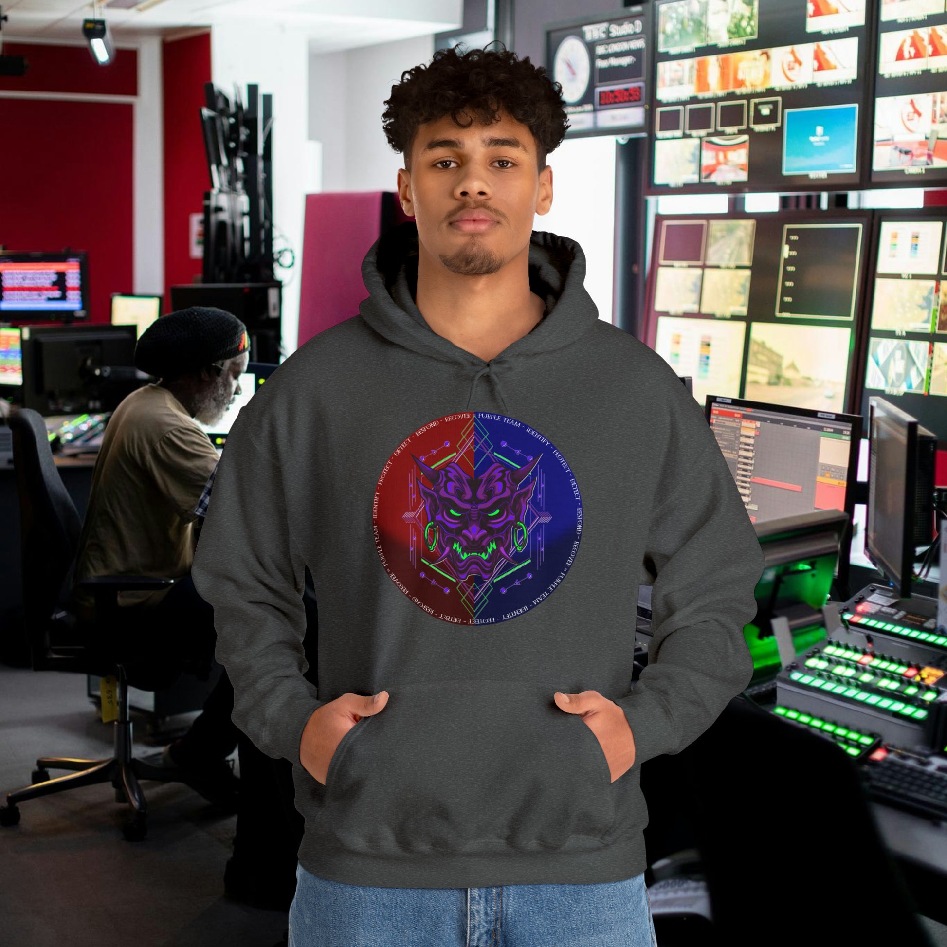 Man wearing a dark gray hoodie with a purple oni demon mask in a red and blue circular background. White text around the circle "Identify, Protect, Detect, Respond, Recover" cybersecurity framework.