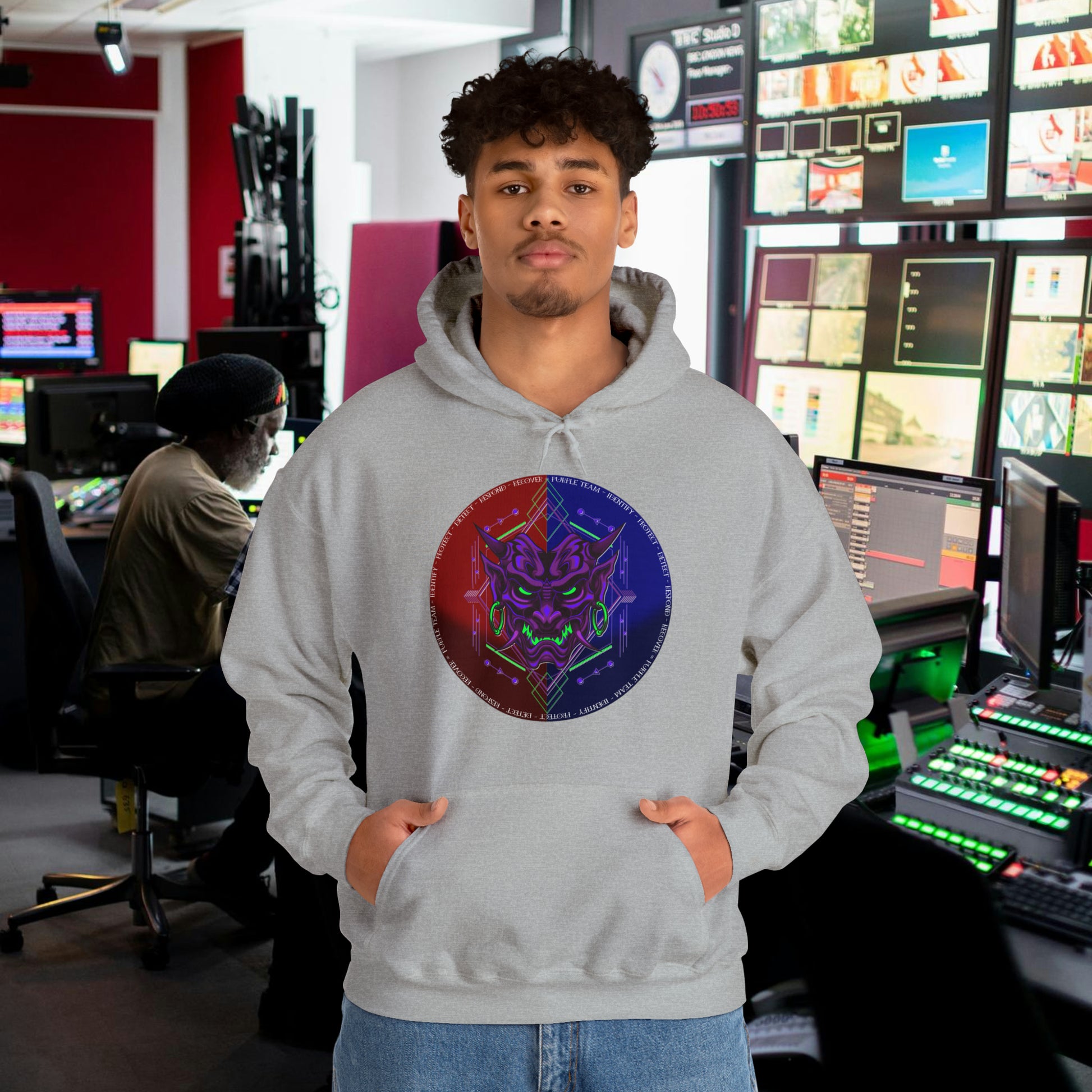 Man wearing a light grey hoodie with a purple oni demon mask in a red and blue circular background. White text around the circle "Identify, Protect, Detect, Respond, Recover" cybersecurity framework.