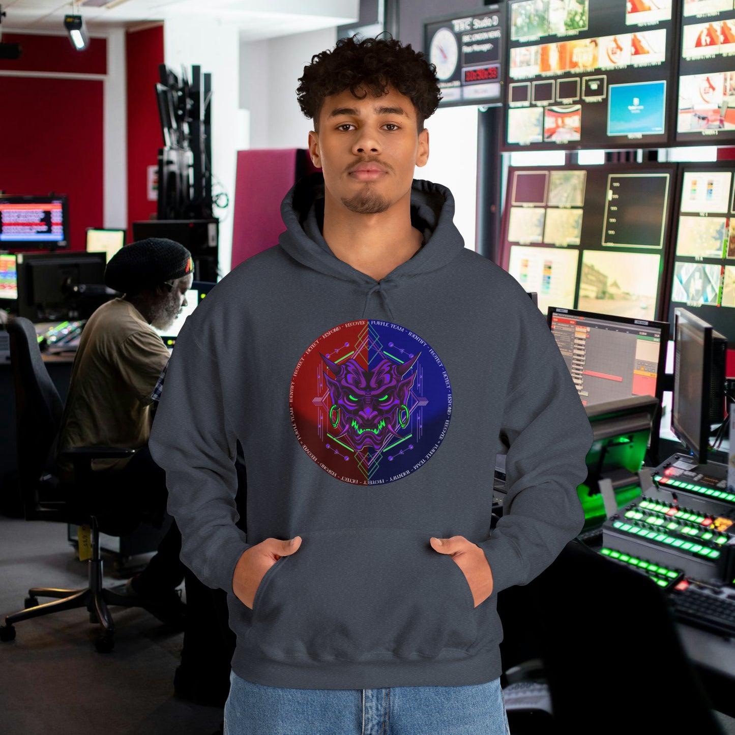 Man wearing a heather navy hoodie with a purple oni demon mask in a red and blue circular background. White text around the circle "Identify, Protect, Detect, Respond, Recover" cybersecurity framework.